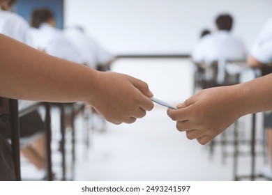 Students secretly take notes and send answers to each other during a school exam. Concept of corruption in the exam room. - Powered by Shutterstock