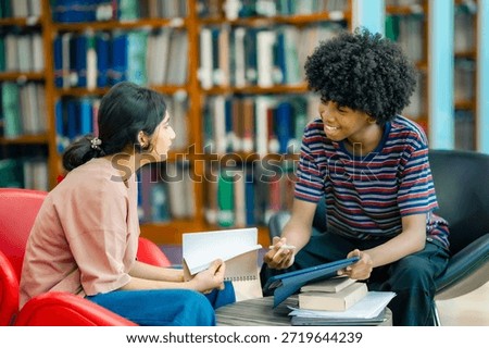 Students sharing ideas during study session in library using tablet representing teamwork learning academic preparation knowledge exchange.