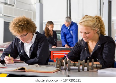 Students Studying An Auto Part Kept On Their Desk In The Vocational School Of Automotive Trade