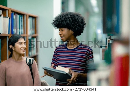 Students talking while selecting books inside library showing learning lifestyle curiosity knowledge seeking academic environment. Students talking while walking through aisel.