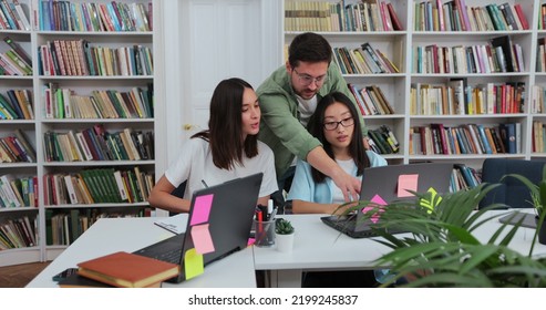 Students team study together using laptop prepare for exam in library, multiethnic young people group talk looking at computer. Education concept.