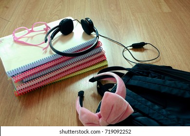 Student's text book with her stuff ,bag,head phones,glasses on wooden floor with copy space