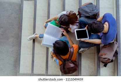 Students university asian together reading book study smiling with tablet at high school campus,college in summer sitting ladder top view.