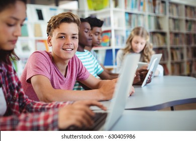 Students using laptop, digital tablet in library - Powered by Shutterstock