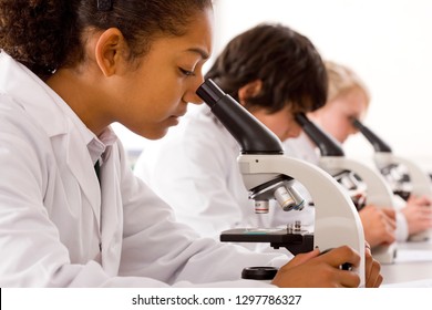 Students using microscopes in school science laboratory 库存照片