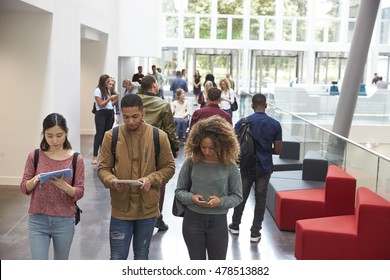 Students Walk In University Campus Using Tablets And Phone