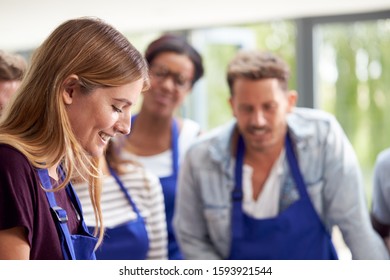 Students Watching Female Teacher Following Recipe In Cookery Class