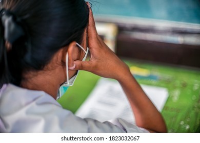 Students Wearing Mask For Protect  Corona Virus Or Covid-19 And Doing Exam Answer Sheets Exercises In Classroom Of School With Stress.