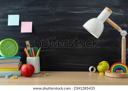 Student's workplace for efficient studying concept. Side view photo of desk lamp, stationary and books on wooden table on chalkboard isolated background with copy-space for text or advertising