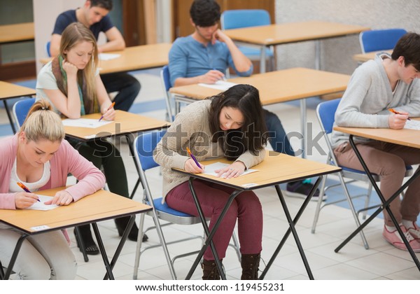 Students writing\
in the exam hall of the\
college
