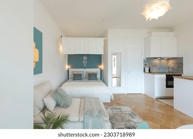 Studio apartment with one double bed and one single bed. There is also parquet flooring, a lamp and a nice canopy. Frontal view - Powered by Shutterstock