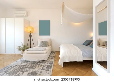 Studio apartment with one double bed and one single bed. There is also parquet flooring, a lamp and a nice canopy. Frontal view - Powered by Shutterstock