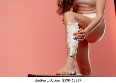 studio beauty shoot on pink background beautiful girl in white underwear applying shaving gel to her leg smooth skin - Powered by Shutterstock