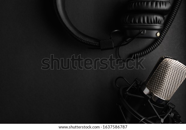 Studio black studio microphone with studio\
headphones on a black background. Banner. Radio, work with sound,\
podcasts.