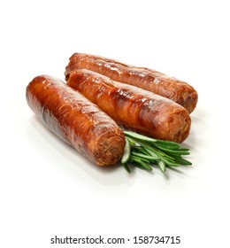 Studio close up of pin sharp focus grilled pork sausages stacked against a white surface with rosemary sprigs and soft shadows. Copy space.