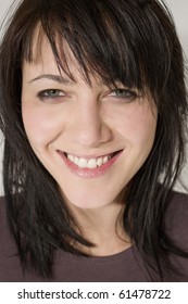 Studio Close Up Portrait Of A Beautiful Young Woman With A Big Cheesy Smile.