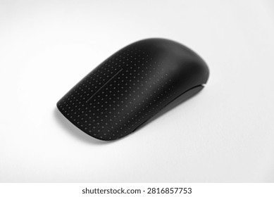 Studio close-up of a black wireless computer mouse with a dotted textured surface placed on a clean white background. Suitable for themes of computer accessories, office equipment, wireless technology, modern workspace tools, and minimalist product photography.