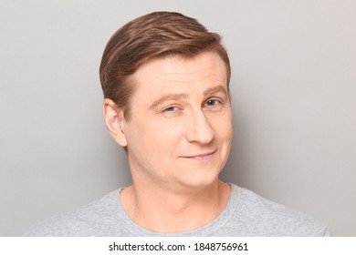 Studio Close-up Portrait Of Blond Mature Man With Happy Expression On Face, With Positive Facial Emotion, Smiling, Looking Straight Ahead. Headshot Over Gray Background