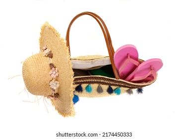 Studio closeup top view shot of pink rubber casual unisex slipper in woven weaving wicker rattan handbag decorated with colorful tassel for summer beach sea weekend vacation on white background.