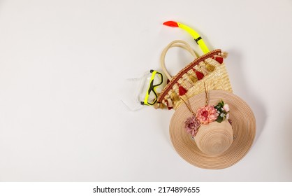 Studio closeup top view shot of snorkel in woven weaving wicker rattan handbag decorated with colorful tassel with woven hat for summer beach sea weekend vacation on white background