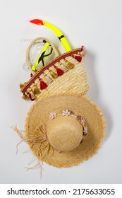 Studio closeup top view shot of snorkel in woven weaving wicker rattan handbag decorated with colorful tassel with woven hat for summer beach sea weekend vacation on white background