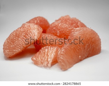 Studio composition of peeled red pomelo slices showing natural cell vesicles texture.
