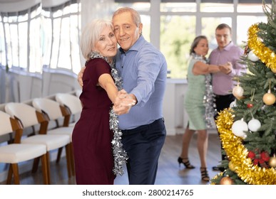 In studio decorated for New Year, elderly man and woman perky dance pair discofox. Energy activity and hobbies