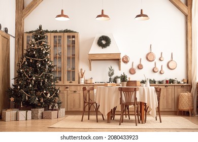 Studio decorations with modern, festive kitchen interior Christmas and New Year decorations, kitchen table, utensils, copper pans on wall and big Christmas tree with presents, winter holidays concept - Powered by Shutterstock