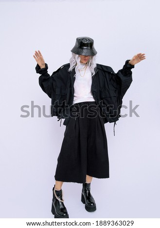 Studio Fashion Portrait Of Blonde Wearing black and White Street Clothes and stylish accessories. Bucket hat and trendy platform boots. Minimalist concept