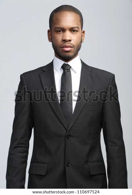 黒いスーツとネクタイを着たアフリカ系アメリカ人のハンサムな若い実業家のスタジオファッションポートレート グレイの背景に分離型 の写真素材 今すぐ編集