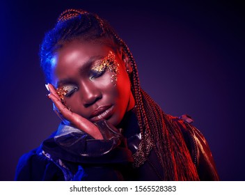 Studio Fashion Portrait Of Young African Ethnicity Woman With Shiny Golden Make Up. Face Close Up. Neon Red And Blue Duotone Trendy Light And Toning.