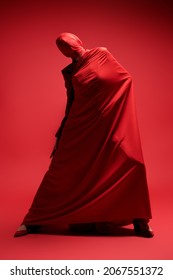 Studio Full Length Portrait Of An Expressive Female Fashion Model Wrapped In Red Fabric Posing On A Red Background. High Fashion Shoot. 