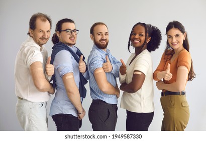 Studio group portrait of happy healthy responsible multiethnic male and female citizens giving thumbs-up after receiving vaccine. Diverse people promoting vaccination during World Immunization Week
