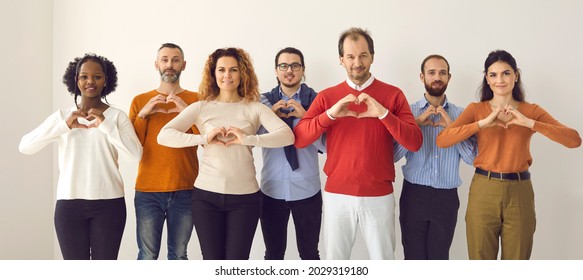 Studio group portrait of thankful youth and senior citizens sending you love, support and gratitude. Team of young and mature people doing heart shape hand gesture isolated on white banner background