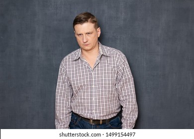 Studio half-length portrait of unhappy fair-haired caucasian young man dressed in casual clothes, being tired or upset, looking sadly in side, standing hunched and hands down, over gray background - Shutterstock ID 1499154497