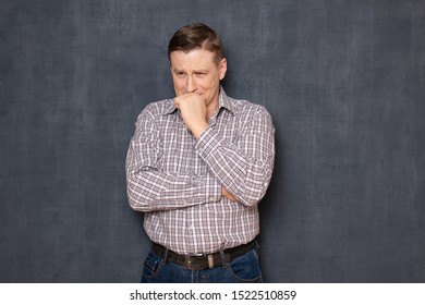 Studio half-length portrait of upset sad man wearing shirt, holding hand near mouth, trying to keep from crying, suffering while thinking about family tragedy or business failure, over gray background - Shutterstock ID 1522510859