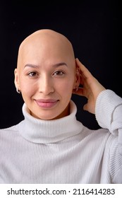 Studio Headshot Portrait Of Happy Smiling Young Caucasian Woman With Shaved Head Against Black Studio Background. Cancer Survivor Beauty Portrait. Hairless Lady In White Casual Shirt Posing