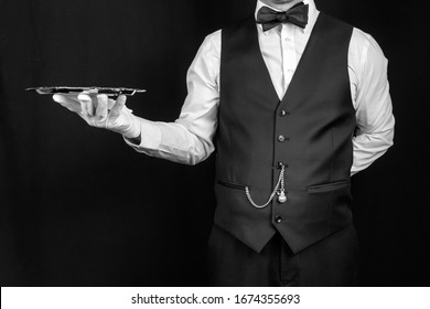 Studio Image Of Butler Or Waiter In Vest And White Gloves Holding Silver Tray. Concept Of Service Industry And Professional Hospitality. Copy Space For Service And Courtesy