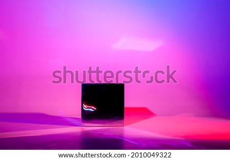 Studio image in futuristic style of dark shiny cube reflecting rays of light, block lonely located in center isolated over purple colored background