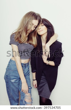Studio lifestyle portrait of two best friends hipster girls wearing stylish outfits, going crazy and having great time together