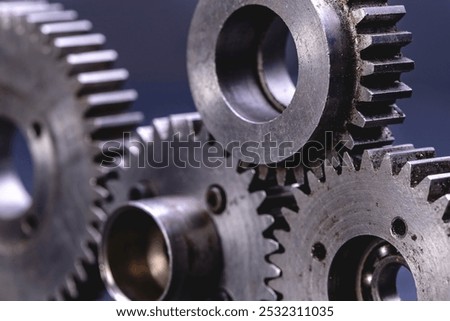 A studio macro shot for a theme of Cogwheel, here three splined gear wheels interlocked horizontally, with a fourth gear wheel interlocked between two of them.