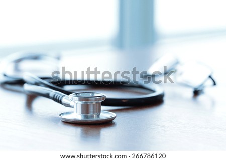 Studio macro of a stethoscope and digital tablet with shallow DOF evenly matched abstract on wood table background copy space