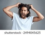 Studio, man and frustrated with pulling of hair for bad news, stress and anxiety on gray background. Angry, male person and expression with screaming for panic attack, mental health and ptsd trauma