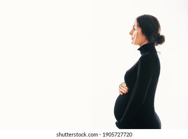 Studio maternity portrait of gorgeous young woman, posing on white background, wearing black turtle neck dress 