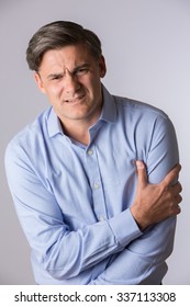 Studio Of Mature Man Clutching Arm As Warning Of Heart Attack
