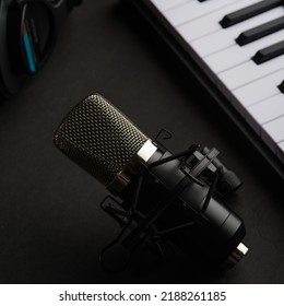 Studio Microphone, Studio Headphones And Midi Keyboard On A Gray Background. Recording Studio, Music Studio. There Are No People In The Photo. Advertising, Banner, Invitation.