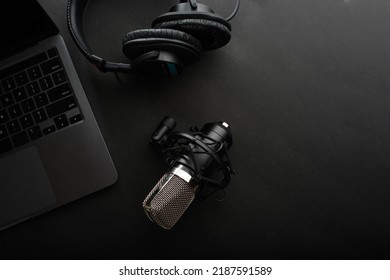 Studio microphone, studio headphones, notebook against a dark gray background. Low angle view. Home office of a journalist, radio worker, blogger, sound engineer, freelancer, musician.