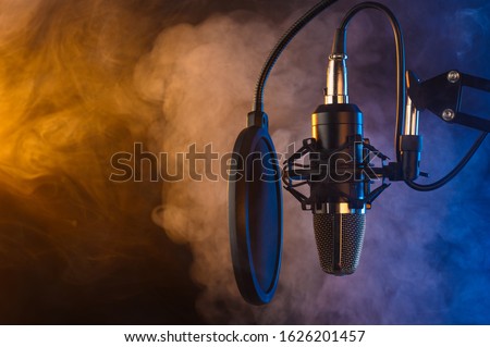 Studio microphone on mic stand against .Color disco background. Vocals and radio, podcasts, colored smoke.