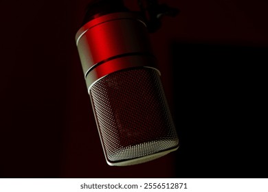 Studio microphone with red lighting against a dark background. Close-up shot of professional condenser microphone for recording and podcasting. Music and audio production concept - Powered by Shutterstock