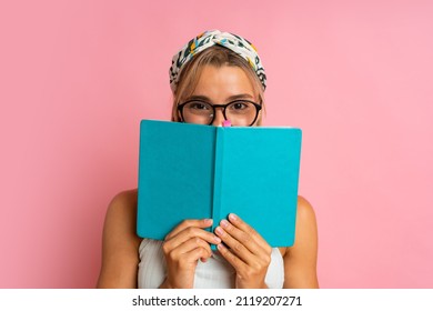 Studio Photo Of Pretty Blond  Student Woman With Suprice Face Posing With Note Book On Pink Background.